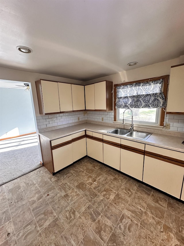 kitchen featuring decorative backsplash, cream cabinets, ceiling fan, and sink