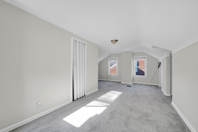 bonus room featuring vaulted ceiling and light colored carpet