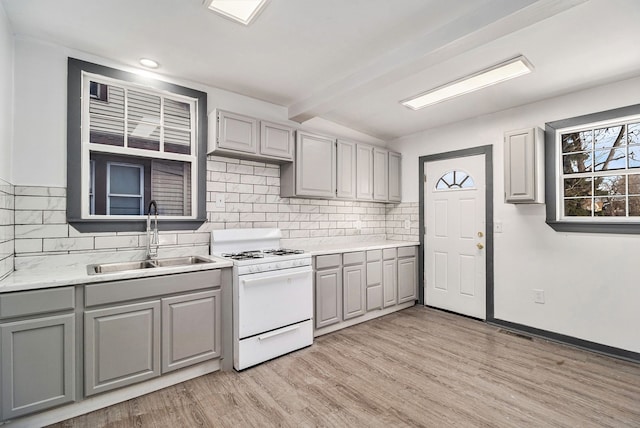 kitchen with gray cabinets, white range, sink, and light hardwood / wood-style flooring