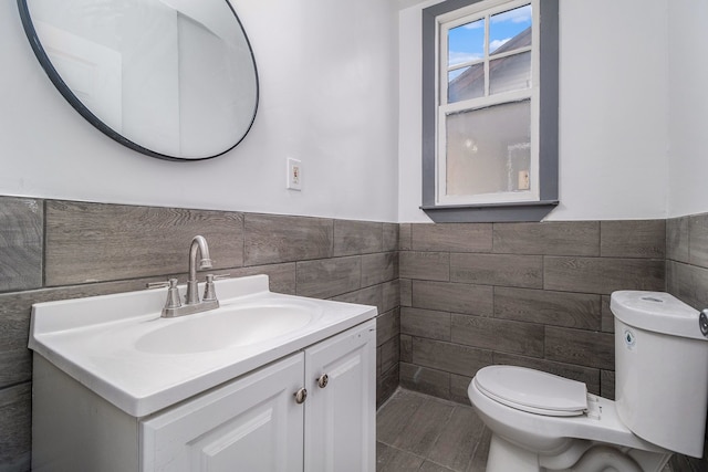 bathroom featuring vanity, tile walls, and toilet