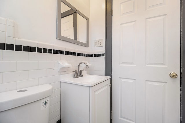 bathroom with vanity, tile walls, and toilet