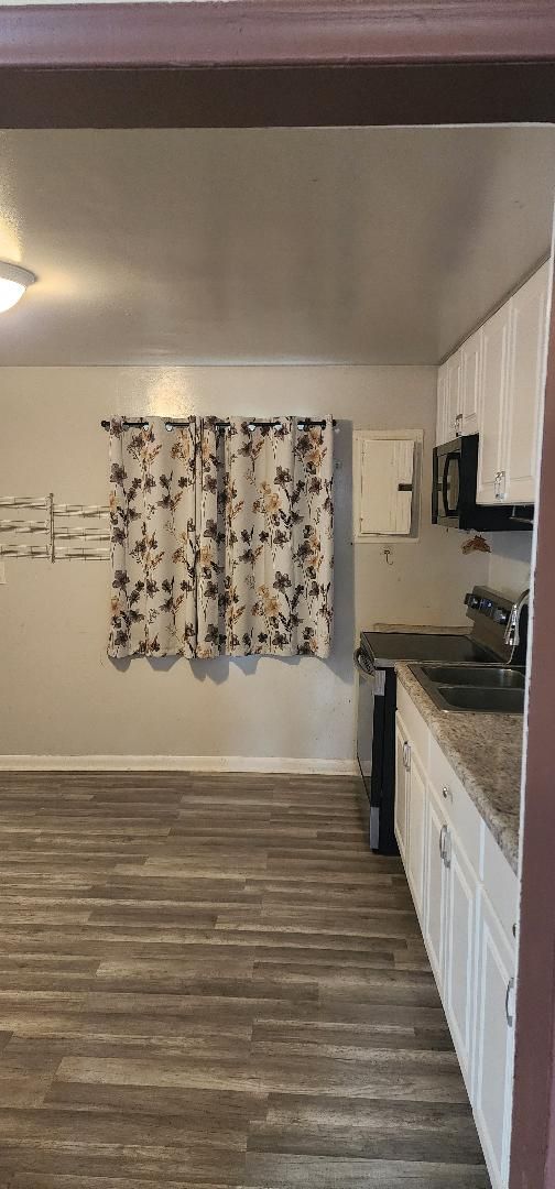 kitchen featuring sink, dark hardwood / wood-style flooring, white cabinetry, and stainless steel range with electric cooktop