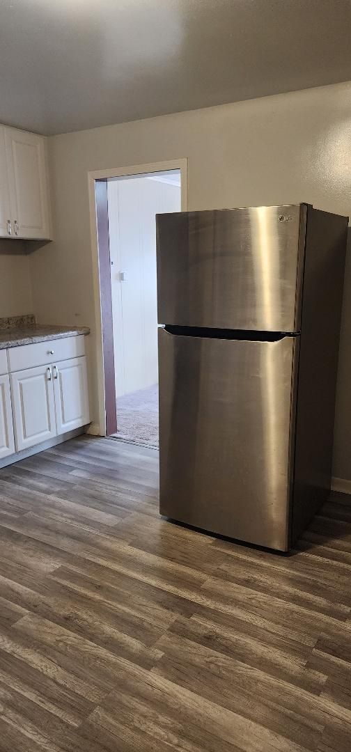 kitchen with white cabinetry, stainless steel fridge, and dark wood-type flooring