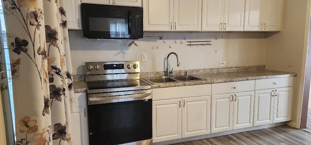 kitchen featuring electric range, white cabinetry, and sink