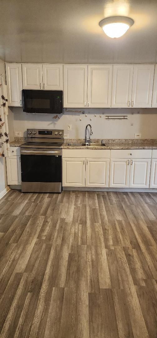 kitchen featuring white cabinets, sink, stainless steel range with electric cooktop, and dark hardwood / wood-style floors