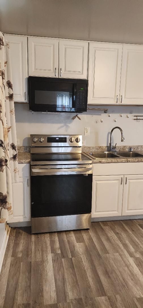 kitchen with electric stove, sink, white cabinets, and dark hardwood / wood-style floors