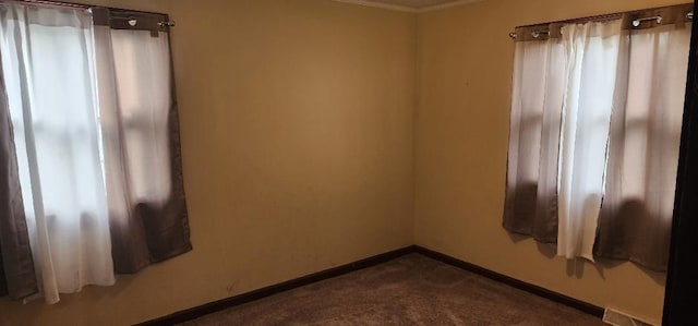 unfurnished room featuring a healthy amount of sunlight, dark carpet, and ornamental molding