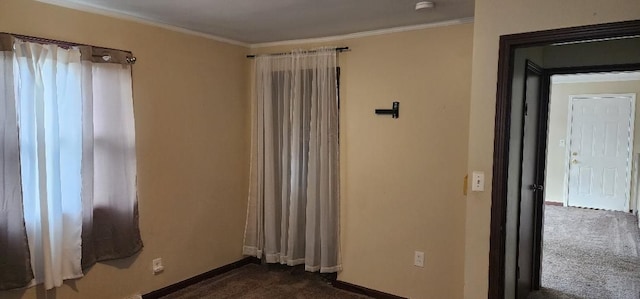 spare room featuring dark colored carpet and crown molding