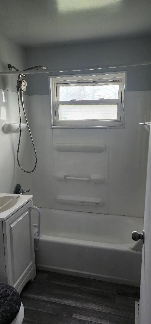 full bathroom with hardwood / wood-style floors, vanity, shower / bath combination, and toilet