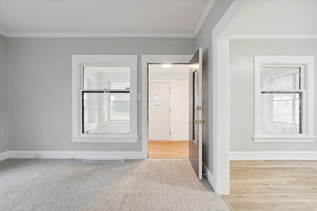 spare room featuring light wood-type flooring and crown molding