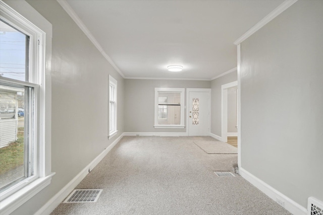 empty room with plenty of natural light, light colored carpet, and crown molding