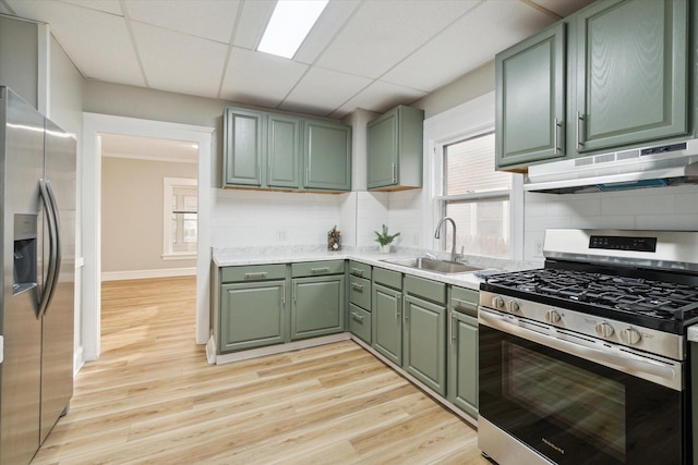 kitchen with sink, stainless steel appliances, light hardwood / wood-style floors, decorative backsplash, and green cabinetry