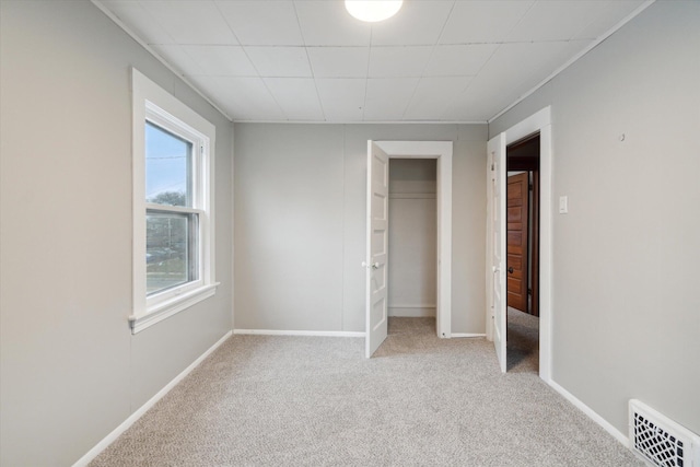 unfurnished bedroom with light colored carpet and a closet