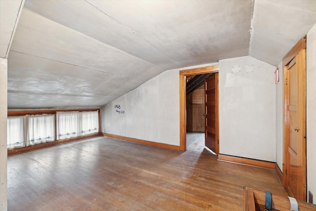 additional living space with hardwood / wood-style flooring and vaulted ceiling