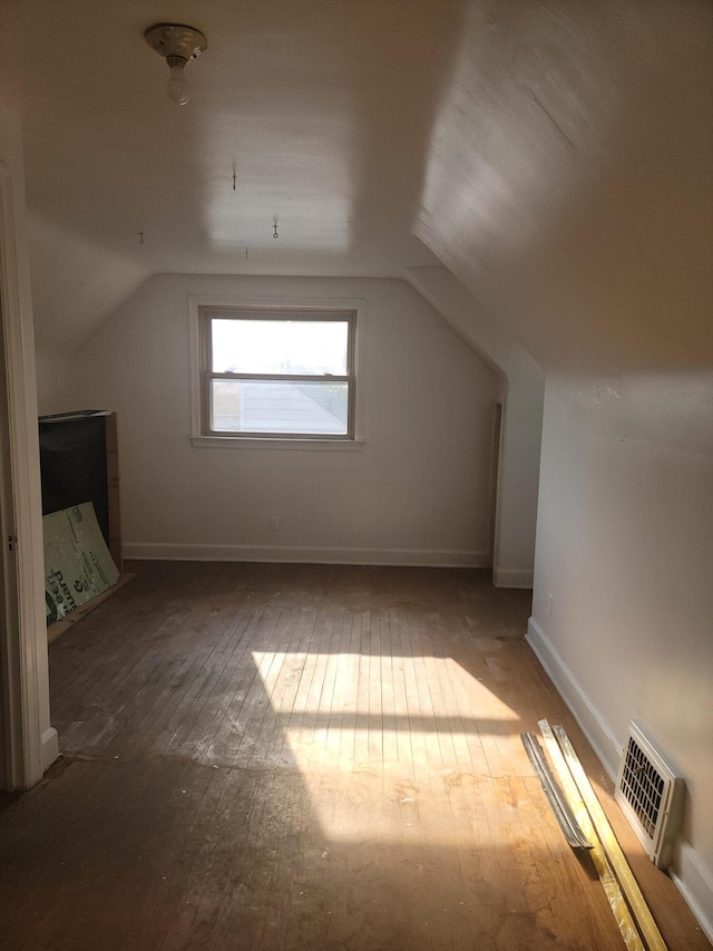 additional living space with hardwood / wood-style flooring and vaulted ceiling