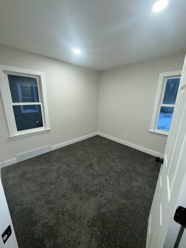 spare room featuring dark carpet