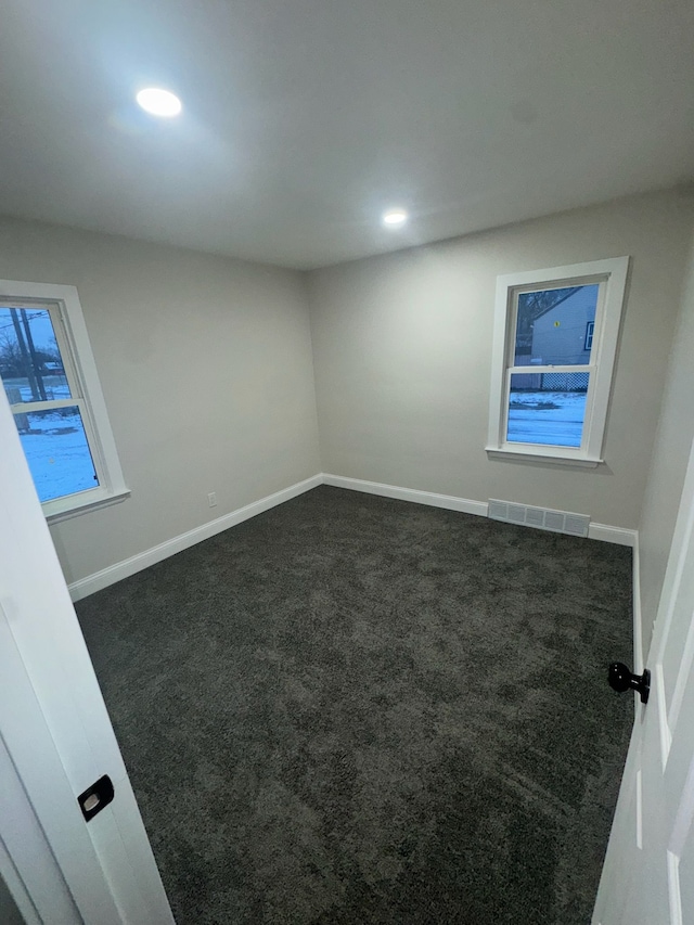 unfurnished room with dark colored carpet