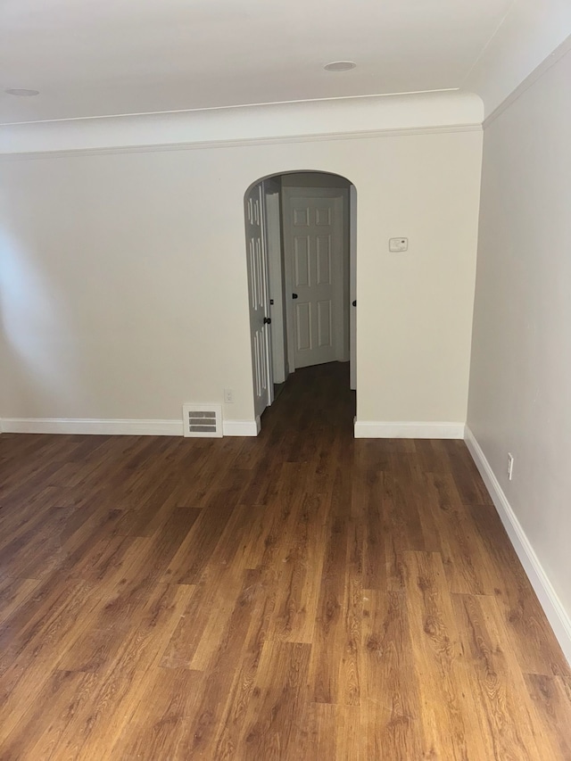 spare room featuring dark hardwood / wood-style floors and crown molding