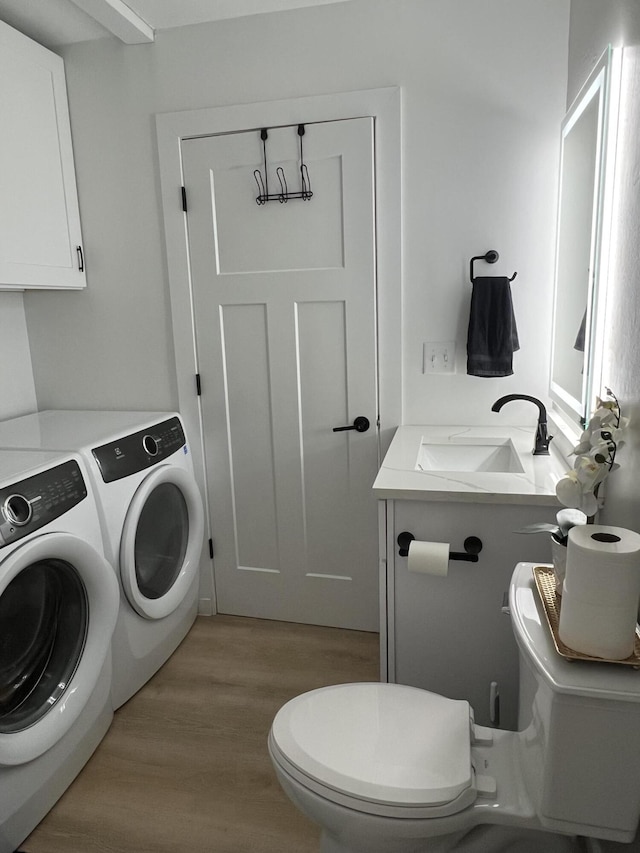 laundry room with light hardwood / wood-style floors, washer and clothes dryer, and sink