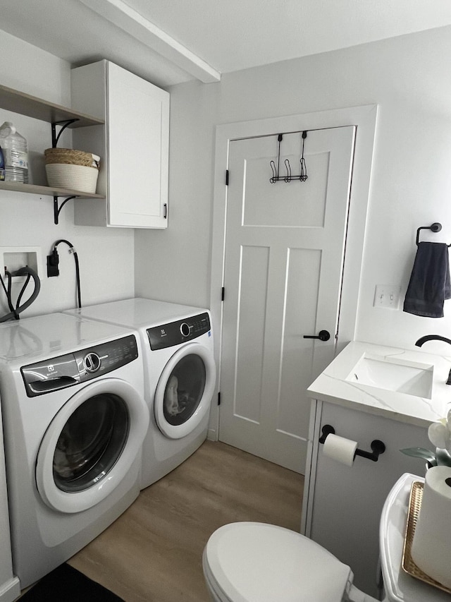 laundry room featuring washer and clothes dryer, light hardwood / wood-style flooring, and sink