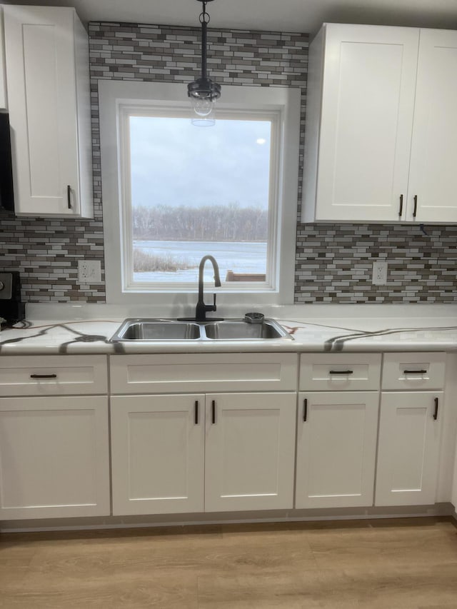 kitchen with white cabinets, tasteful backsplash, light hardwood / wood-style flooring, and sink