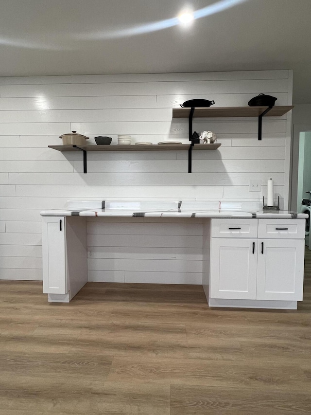 interior space featuring white cabinetry, wooden walls, and light hardwood / wood-style flooring