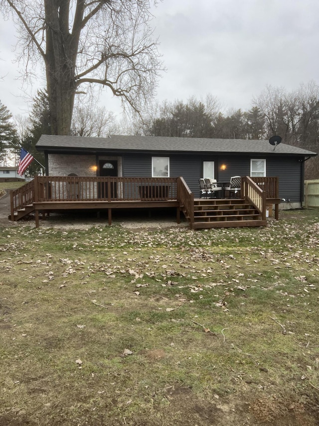 rear view of property featuring a yard and a wooden deck