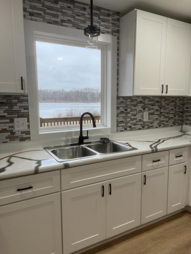 kitchen with backsplash, light hardwood / wood-style flooring, white cabinetry, and sink