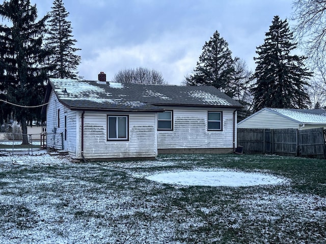 snow covered rear of property featuring a yard