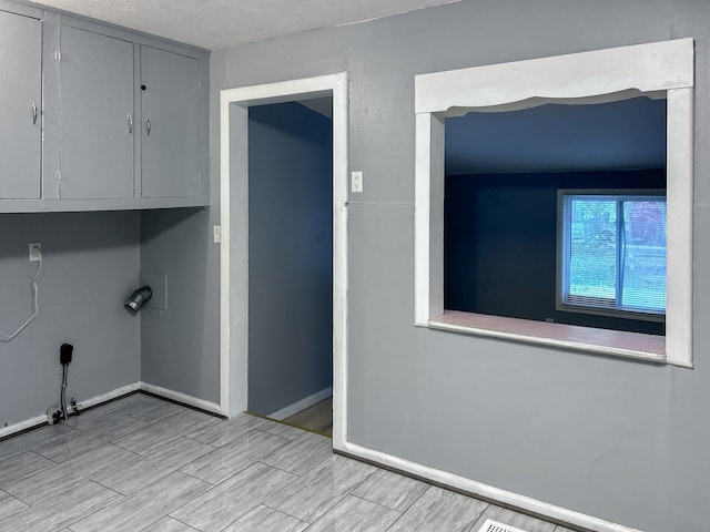 washroom with cabinets, a textured ceiling, and light wood-type flooring