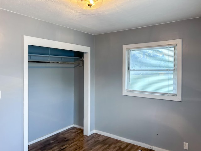 unfurnished bedroom featuring dark hardwood / wood-style flooring and a closet