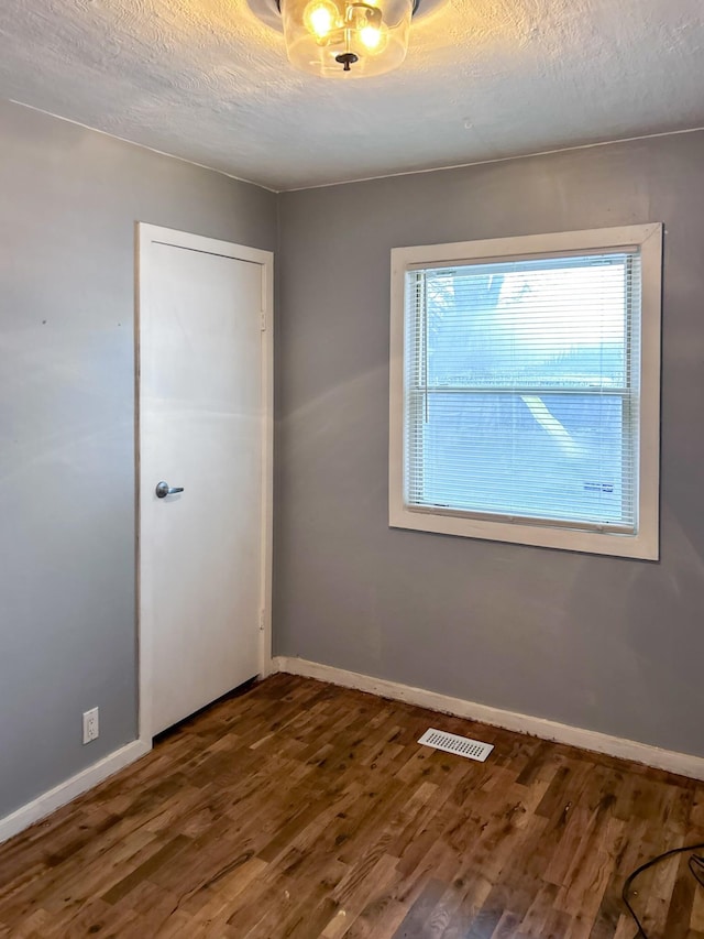 unfurnished room featuring hardwood / wood-style floors and a textured ceiling