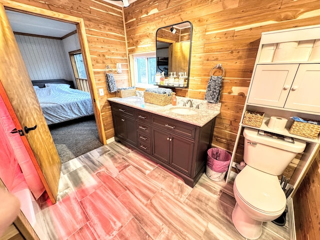 bathroom with vanity, toilet, and wooden walls