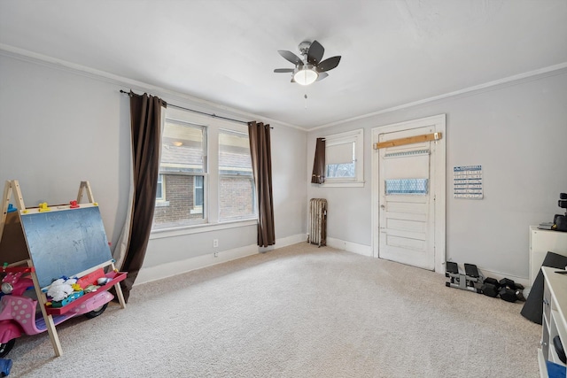 rec room featuring radiator heating unit, light colored carpet, ceiling fan, and ornamental molding