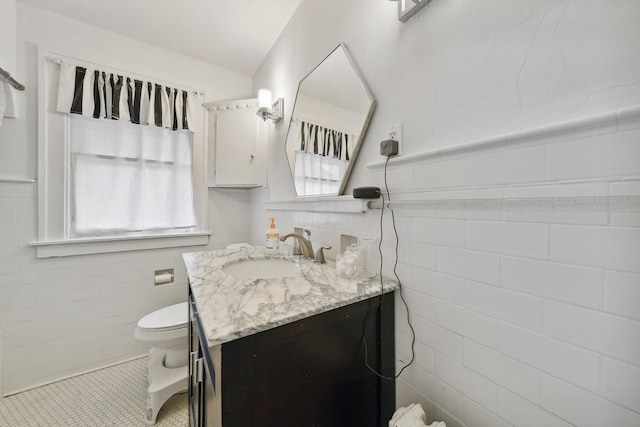 bathroom with tile patterned floors, vanity, tile walls, and toilet