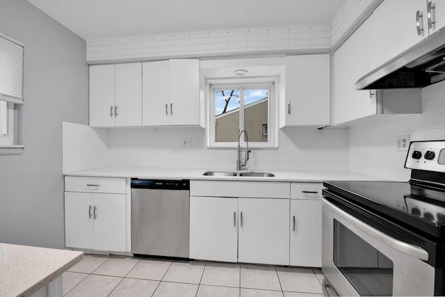 kitchen with appliances with stainless steel finishes, light tile patterned floors, white cabinetry, and sink