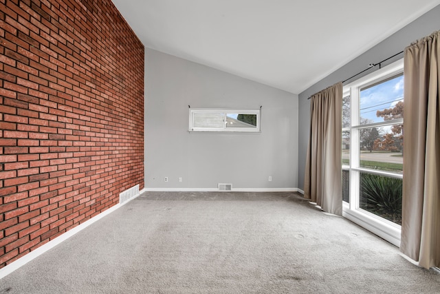 carpeted empty room featuring brick wall and vaulted ceiling