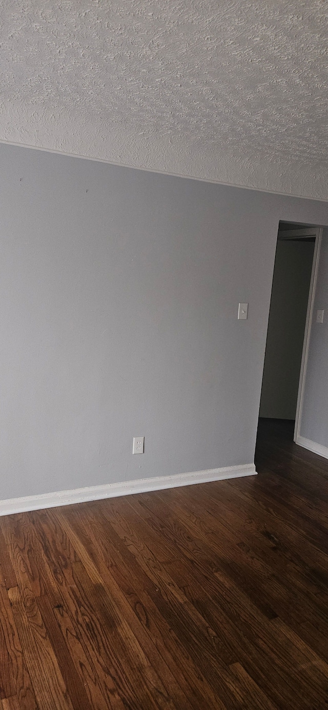 unfurnished room featuring a textured ceiling and dark wood-type flooring