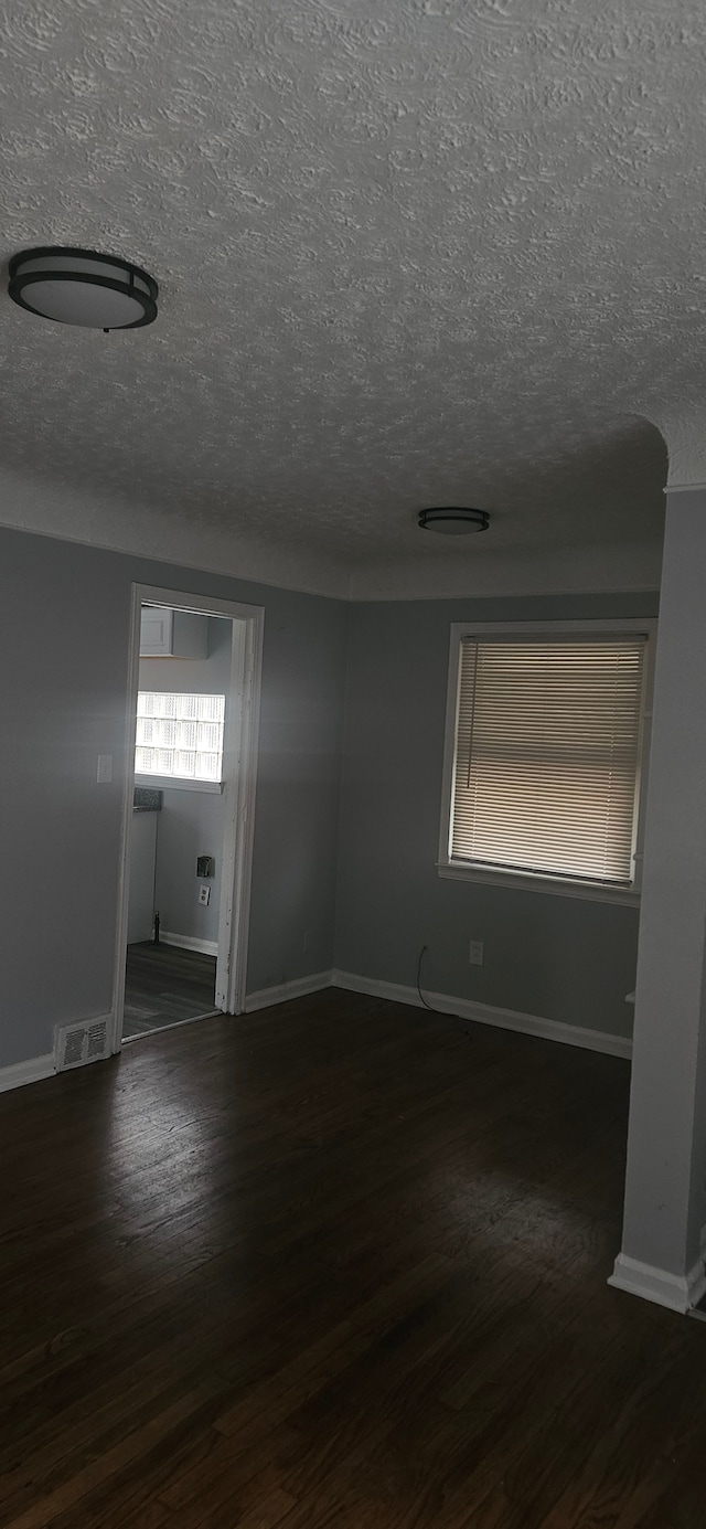 unfurnished room with a textured ceiling and dark wood-type flooring