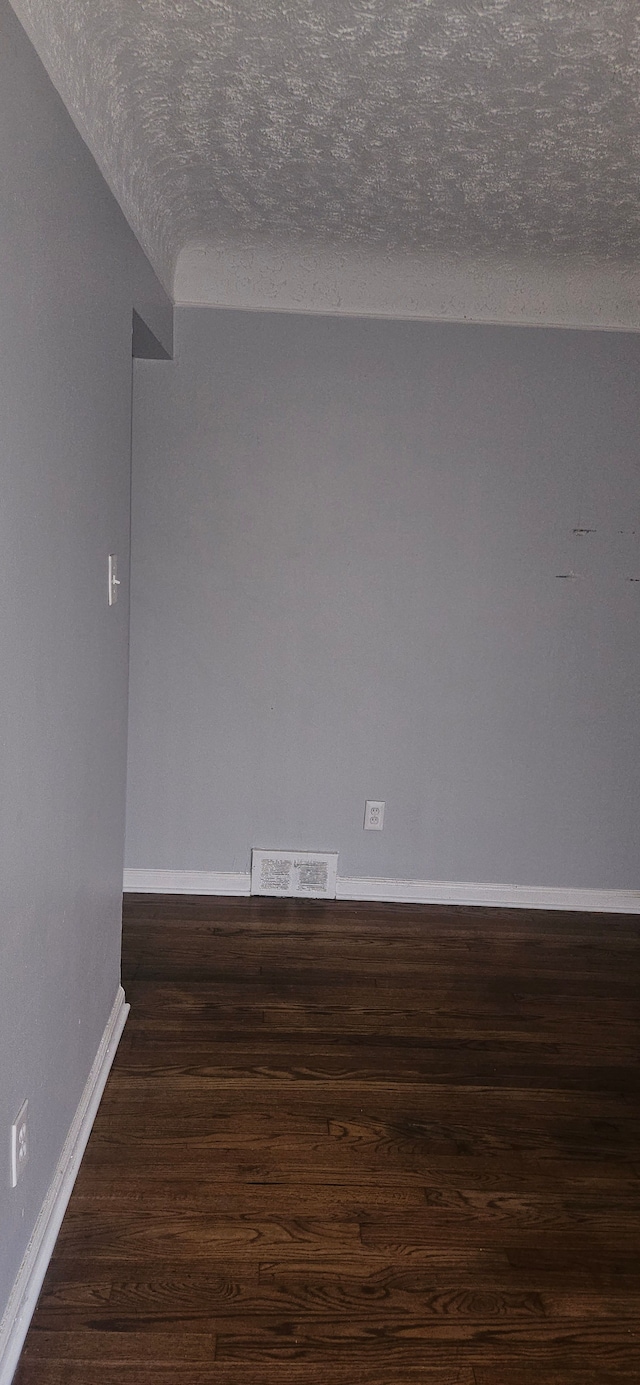 empty room with a textured ceiling and dark wood-type flooring