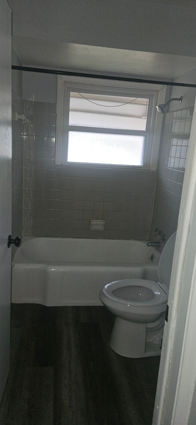 bathroom with tiled shower / bath, wood-type flooring, toilet, and a wealth of natural light