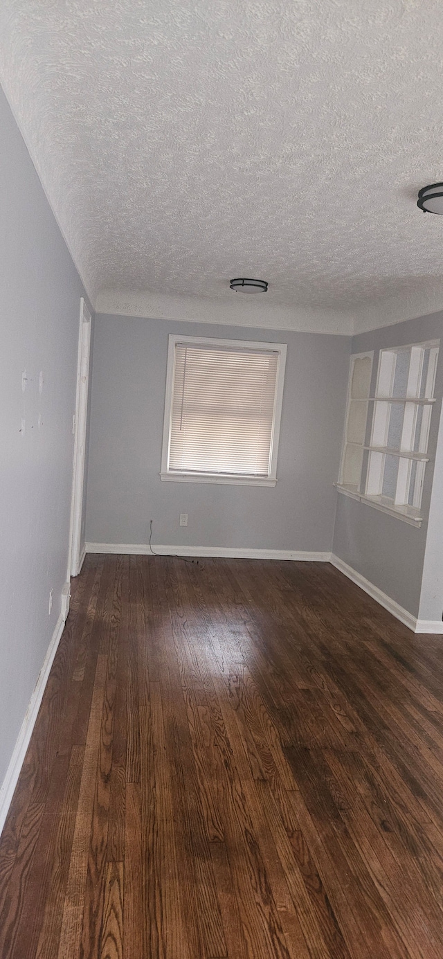 unfurnished room with a textured ceiling and dark hardwood / wood-style floors