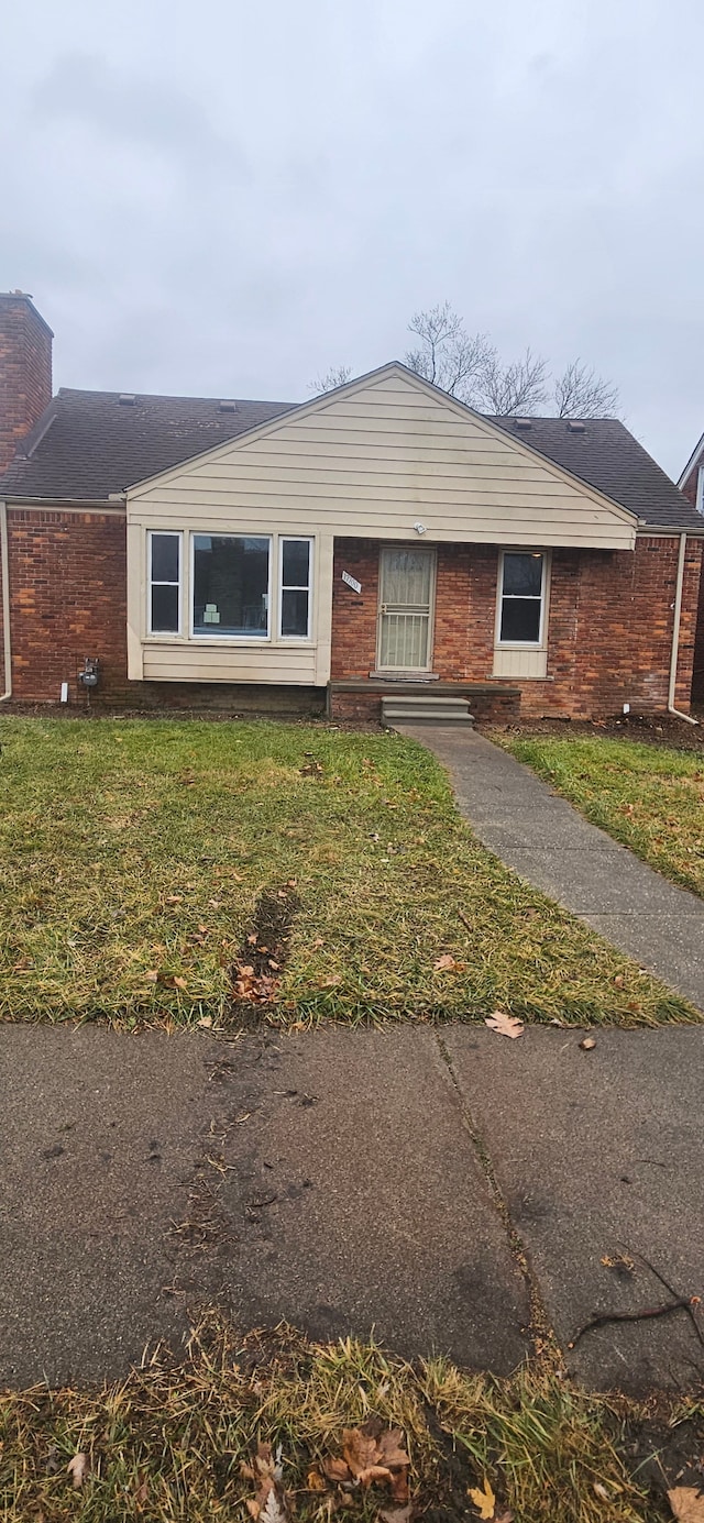 view of front of house featuring brick siding and a front yard