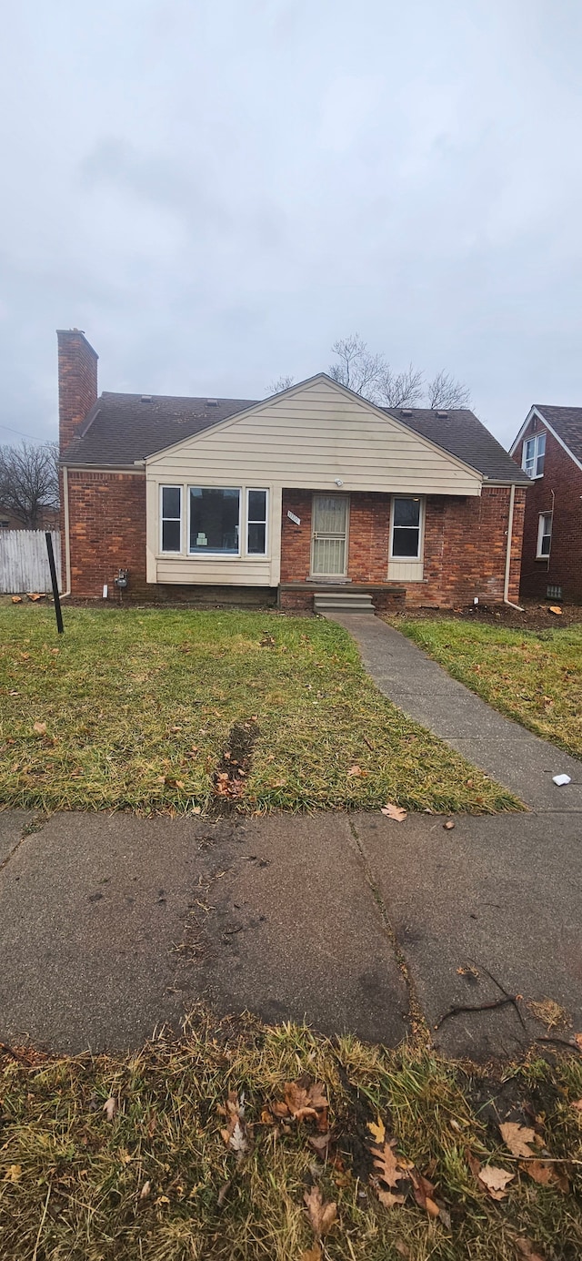 single story home with brick siding, a chimney, and a front lawn