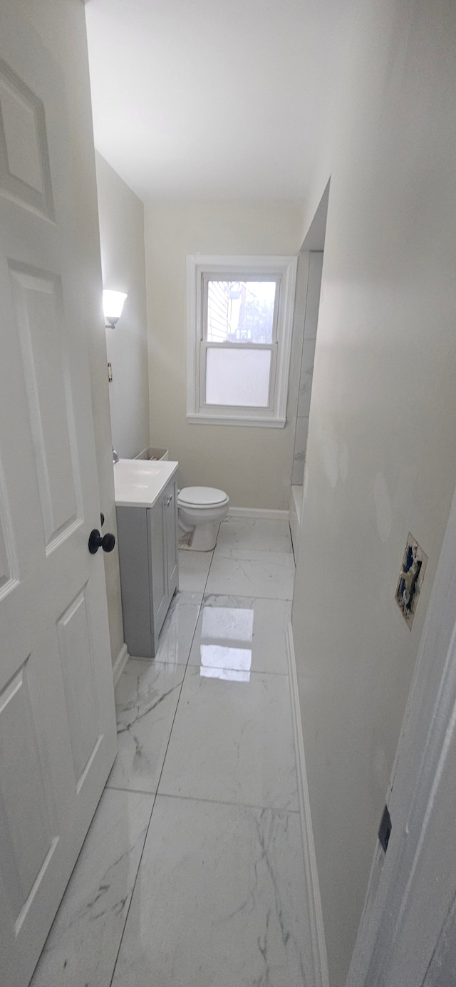 bathroom with toilet, marble finish floor, baseboards, and vanity