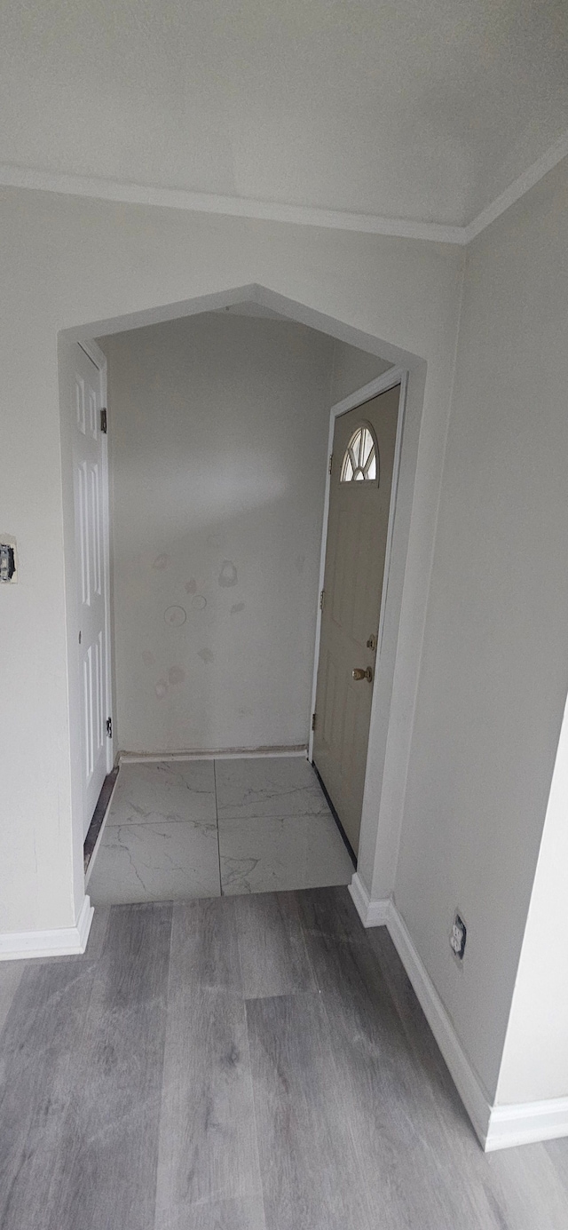 interior space featuring ornamental molding, arched walkways, marble finish floor, and baseboards