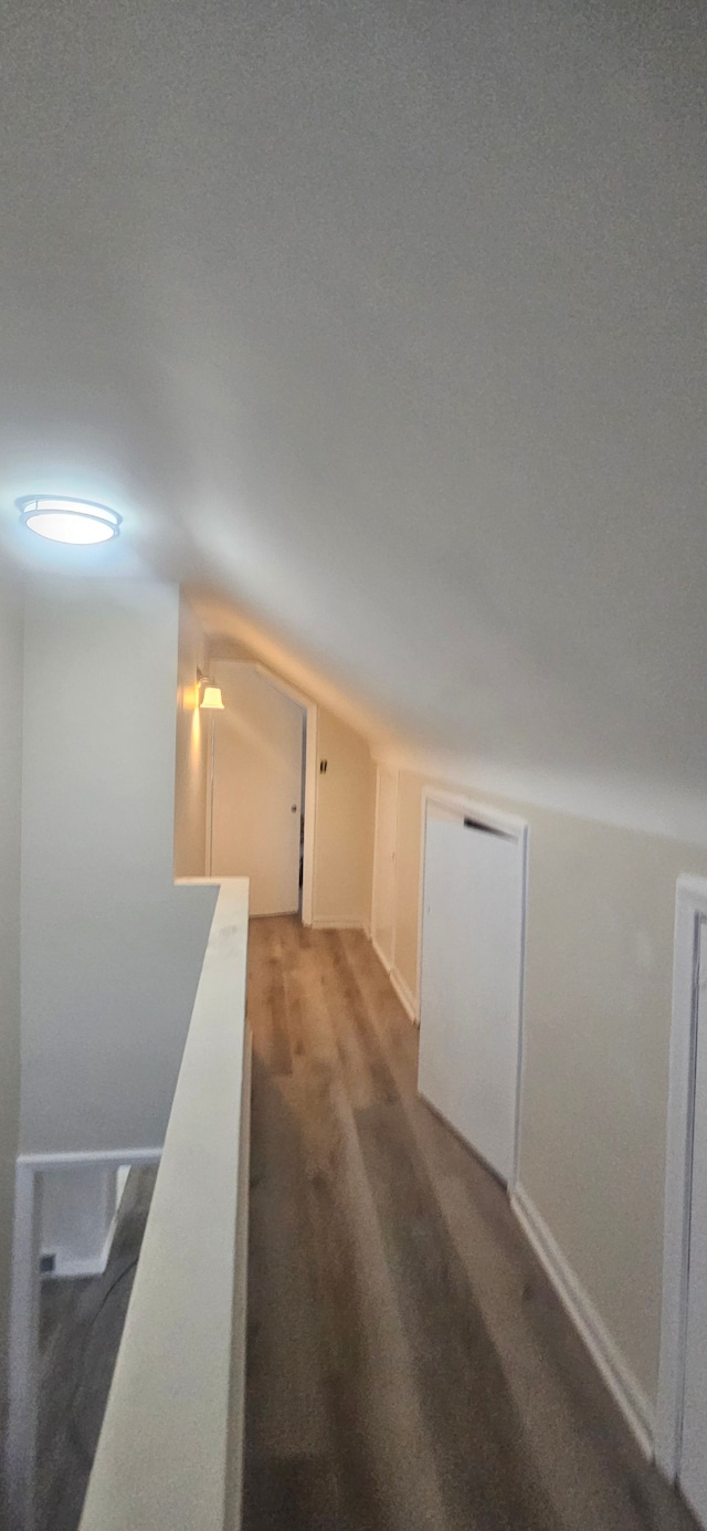 hall with vaulted ceiling and wood finished floors