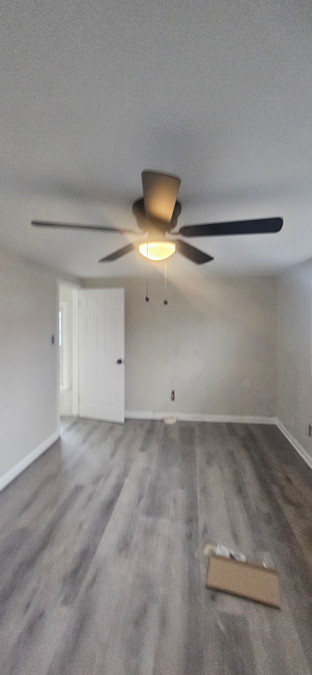 empty room with ceiling fan, baseboards, and wood finished floors