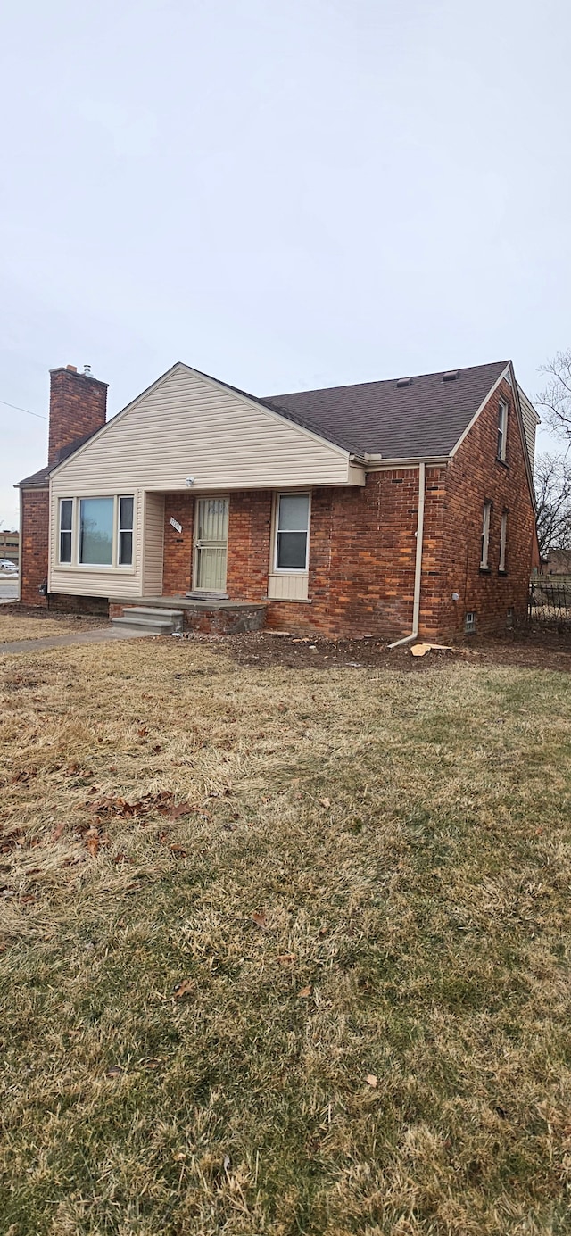 ranch-style house with brick siding, a chimney, and a front yard