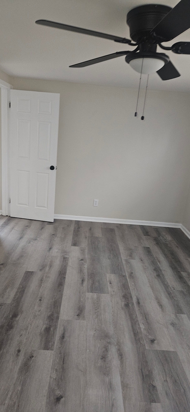 unfurnished room featuring ceiling fan, wood finished floors, and baseboards